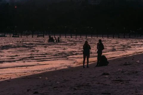 Two Backpacker walking on the beach at sunset Stock Photos