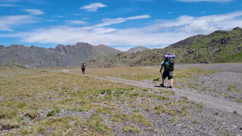 Two backpackers hiking on trail in high altitude mountain valley Stock Footage 282041245