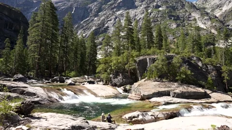 Two Backpackers Relaxing with Scenic View over the Mountains and Waterfall Stock Footage 242024968