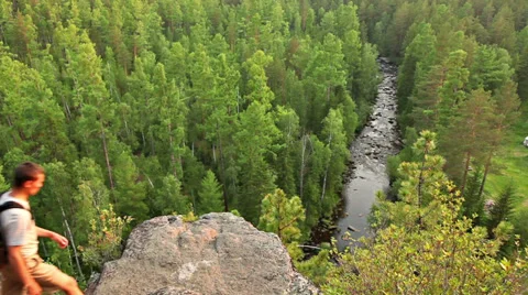 Two backpackers walk high rock above forest Stock Footage 39832014
