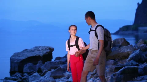 Two backpackers walk on rocky coast of big lake Stock Footage 39589955