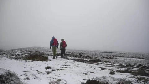 Two backpackers walking through snowy moorland during winter. Stock Footage 337612795