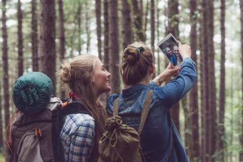 Two backpacking friends making selfie in forest. Stock Photos