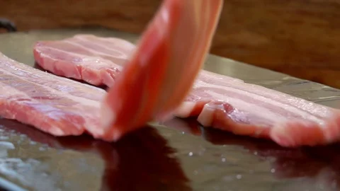 Two bacon strips are stacked on a hot stone grill Stock Footage 102771403