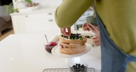 Two bakers are placing blueberries and lemon slices on island, prompted by Stock Footage 347307516