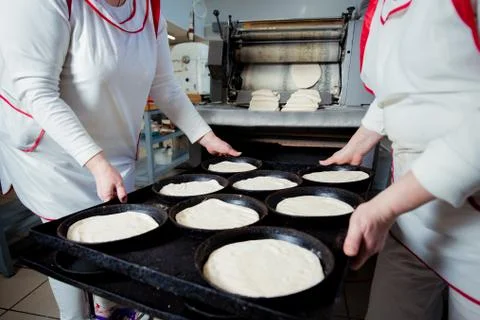 Two bakers hold baking forms with pizza blanks Stock Photos