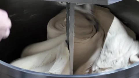 Two bakers knead the dough for bread in a dough mixer in an industrial bakery. Stock Footage 245560074