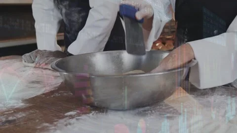 Two bakers pressing dough on bakery bench, right baker scraping bowl, forming Stock Footage 332625555