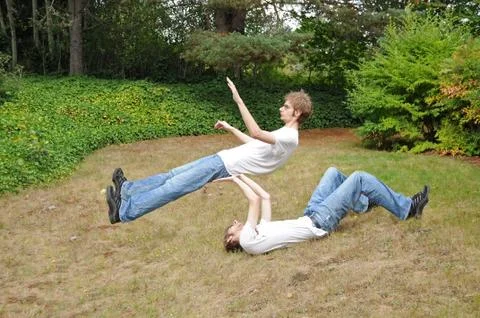 Two balancing clones practicing their street performance circus routine in th Stock Photos