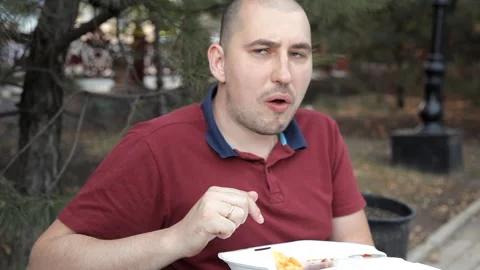 Two bald guys are sitting in the park and eating sandwiches and french fries Stock Footage 95762990