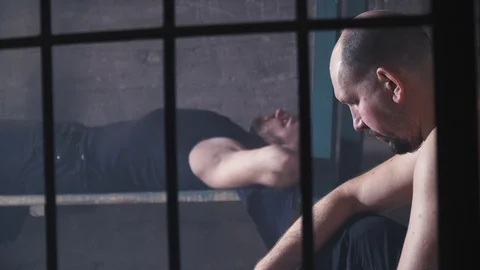 Two bald inmates with beards are in the cell, view from behind bars, 4k Stock Footage 104047302