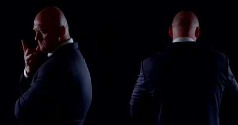Two bald men dressed in dark business suits. they slowly rotate on a black 库存影片 134733862