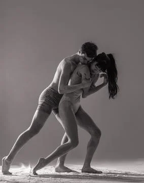 Two ballet dancers perform dance against background of white flour cloud in a Stock Photos