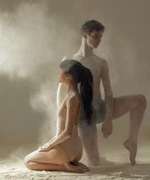 Two ballet dancers perform dance against background of white flour cloud in a Stock Photos