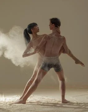 Two ballet dancers perform dance against background of white flour cloud in a Stock Photos