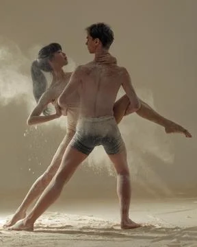Two ballet dancers perform dance against background of white flour cloud in a Stock Photos
