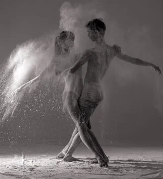 Two ballet dancers perform dance against background of white flour cloud in a Photos