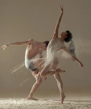 Two ballet dancers perform dance against background of white flour cloud in a Stock Photos