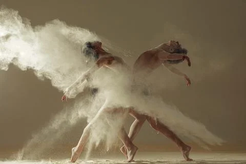 Two ballet dancers perform dance against background of white flour cloud in a Stock Photos