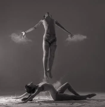 Two ballet dancers perform dance against background of white flour cloud in a Stock Photos