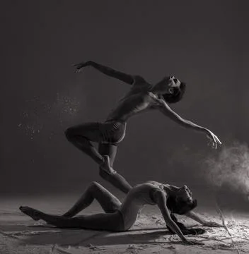 Two ballet dancers perform dance against background of white flour cloud in a Photos