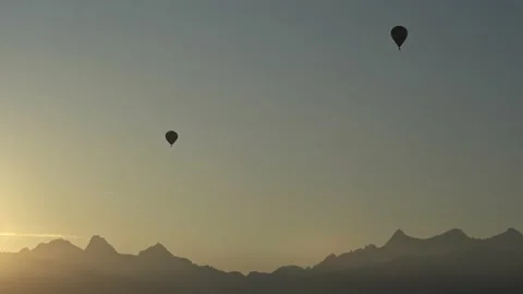 Two balloons fly along the mountains. Mountains and balloons in silhouette Stock Footage 143667779