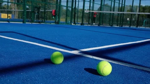 Two balls in the foreground and people playing paddle tennis in the background. Stock Footage 162693740