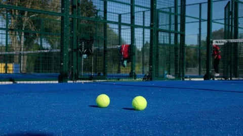 Two balls in the foreground and people playing paddle tennis in the background. Stock Footage 162693757
