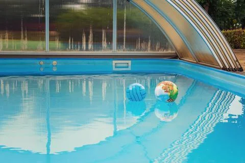 Two balls left alone on water surface in blue pool Stock Photos
