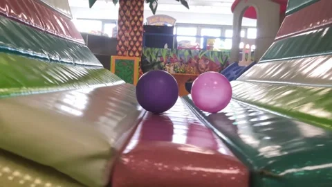 Two balls roll and fall from a children's carousel in a playground Stock Footage 151656974