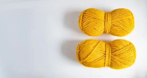 Two balls of yellow thread for knitting or crocheting on a light background Stock Photos