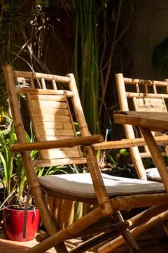 Two bamboo chairs and a table in a garden setting with dappled sunlight. Stock Photos