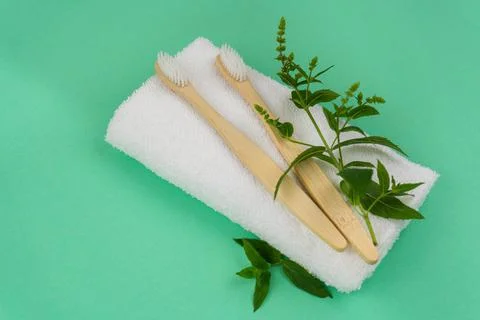 Two bamboo toothbrushes with mint sprigs and a white towel Stock Photos