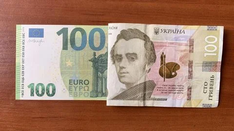 Two banknotes laid side by side on a wooden table. One is a 100 Euro note with 스톡 사진