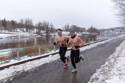 Two bare-chested mans runs along a snow-covered embankment Stock Photos