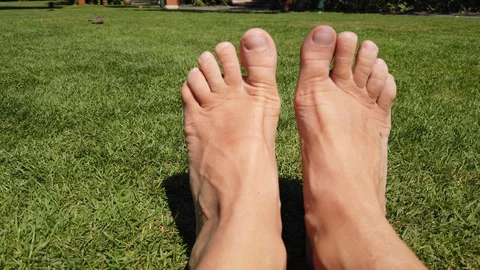 Two bare feet moving funny on a green lawn. Holiday concept. Stock Footage 109534690