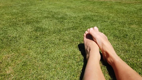 Two bare feet scratching each other on a green lawn. Stock Footage 109534544
