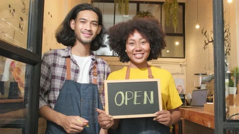 Two barista partners write and show an open sign, new business entrepreneurs. Stock Footage 196662494