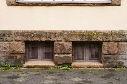 Two basement windows in a stone wall covered with metal mesh. Stock-Fotos