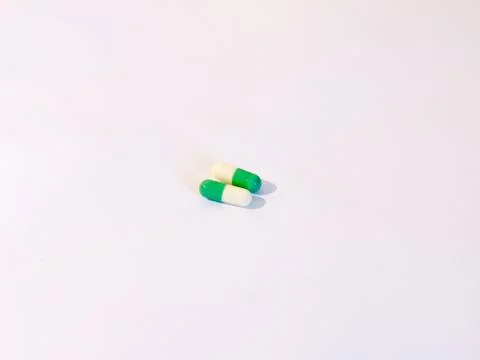 Two basic generic pills on a white background white and green drugs Stock Photos