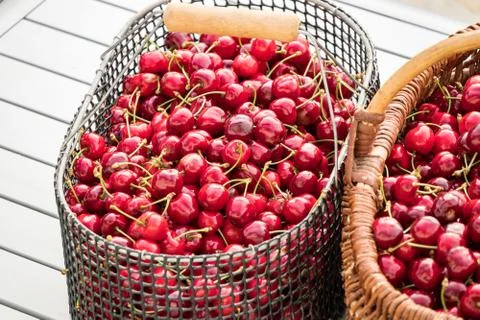 Two baskets filled with beautiful red cherries on a garden table Stock Photos
