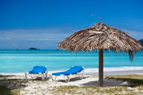 Two beach chairs and a fixed umbrella on a caribbean beach. Stock Photos