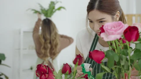 Two beautiful Asian florists work together in her own shop. Video stock 244928018