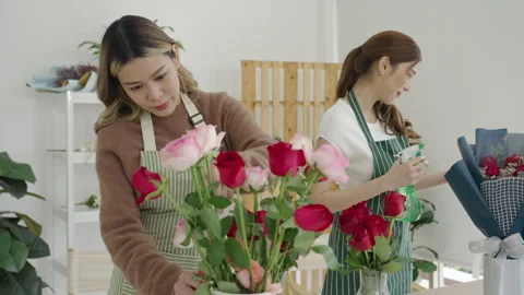 Two beautiful Asian florists work together in her own shop. Video stock 244928516
