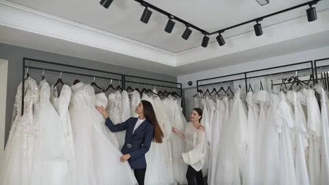 Two beautiful brides choose a beautiful wedding dress in a wedding salon. Stock Footage 322042511