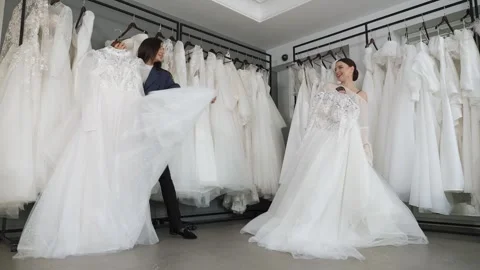 Two beautiful brides choose a beautiful wedding dress in a wedding salon. Stock Footage 322215591