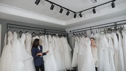 Two beautiful brides choose a beautiful wedding dress in a wedding salon. Stock Footage 323364039