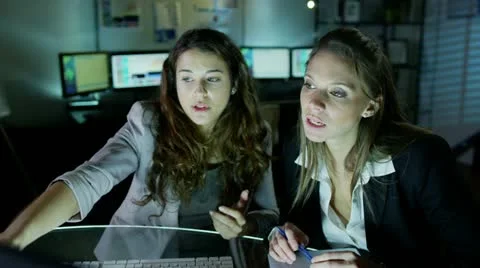 Two beautiful business women working late into the night Stock Footage