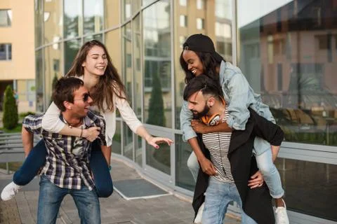 Two beautiful couples having fun near the glass building. Young and attractive Stock Photos