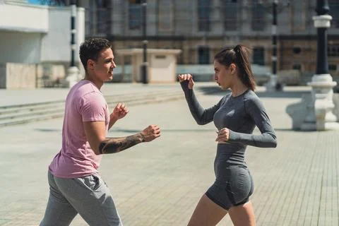 Two beautiful friends, male and female, training kickbox in the city Stock Photos
